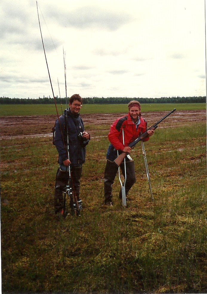 Patrick carrying fishing rods and Gav on crutches holding shotgun